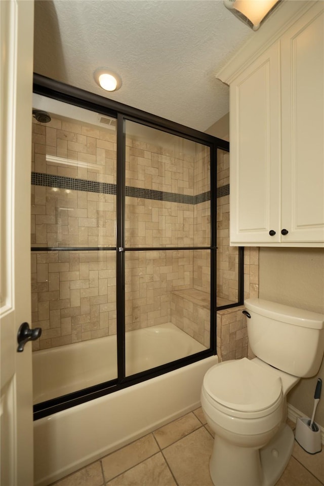 bathroom featuring tile patterned flooring, toilet, enclosed tub / shower combo, and a textured ceiling