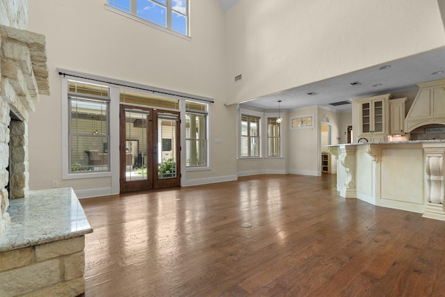 235 Fm 3313, Crockett, TX 75835 - unfurnished living room featuring a stone fireplace, healthy amount of natural light, dark wood finished floors, and a towering ceiling