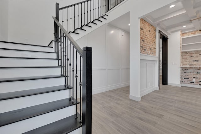 staircase with beamed ceiling, hardwood / wood-style floors, and coffered ceiling