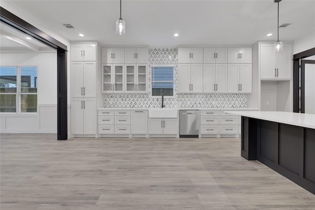 kitchen featuring light wood-type flooring, stainless steel dishwasher, sink, decorative light fixtures, and white cabinets