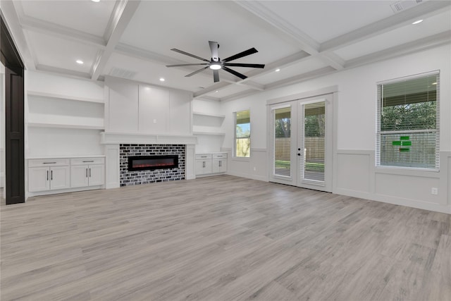 unfurnished living room with coffered ceiling, beam ceiling, a tiled fireplace, and light hardwood / wood-style flooring