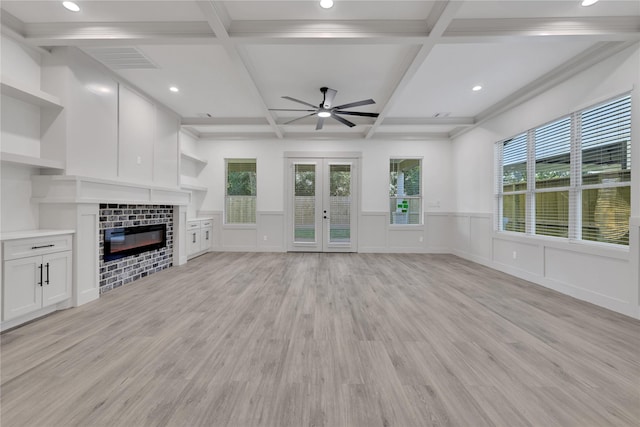 unfurnished living room with a tile fireplace, french doors, coffered ceiling, and light wood-type flooring