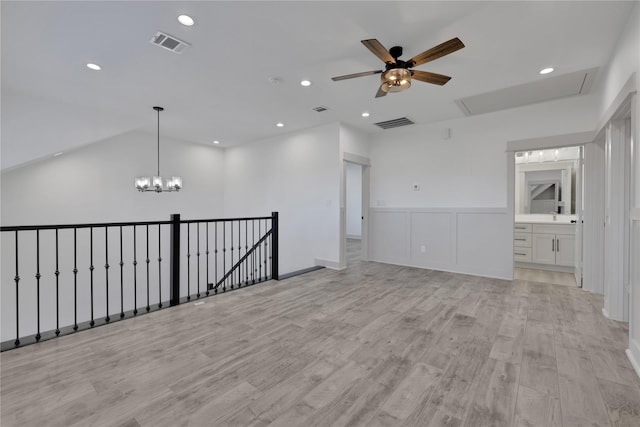 unfurnished room featuring ceiling fan with notable chandelier and light hardwood / wood-style floors