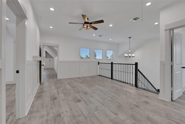 interior space with ceiling fan with notable chandelier and light hardwood / wood-style floors