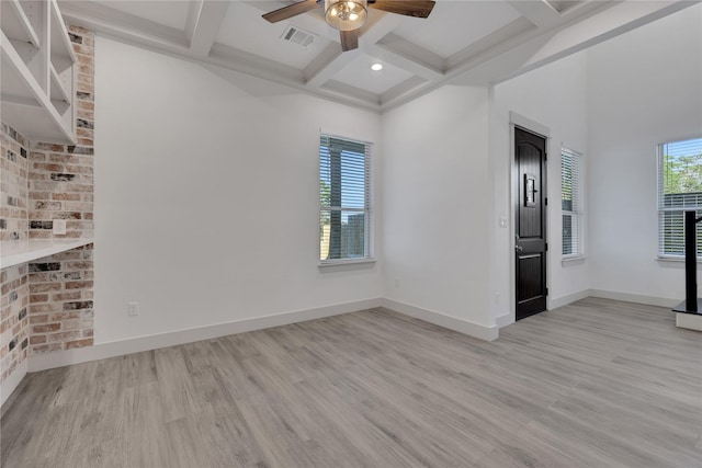 empty room featuring a wealth of natural light, light hardwood / wood-style flooring, beamed ceiling, and coffered ceiling