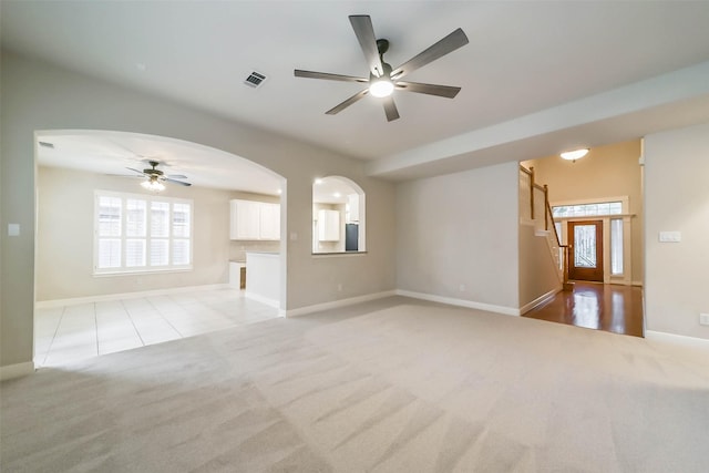 unfurnished living room featuring light carpet, plenty of natural light, and ceiling fan