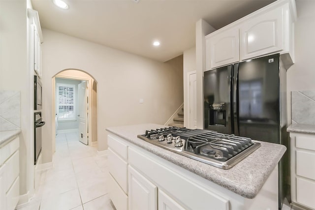 kitchen featuring white cabinets, black appliances, light tile patterned floors, and a kitchen island