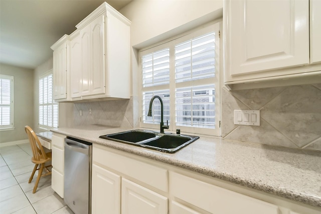 kitchen featuring backsplash, stainless steel dishwasher, sink, light tile patterned floors, and white cabinets