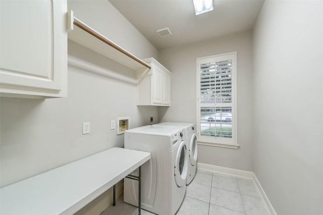 clothes washing area featuring washer and dryer, light tile patterned floors, and cabinets