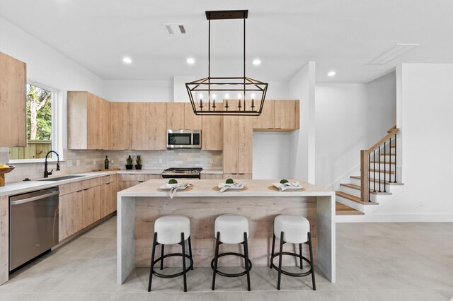 kitchen with visible vents, modern cabinets, a sink, light brown cabinets, and stainless steel appliances