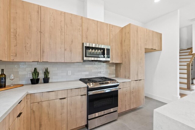 kitchen with appliances with stainless steel finishes, tasteful backsplash, light brown cabinetry, and light tile patterned flooring