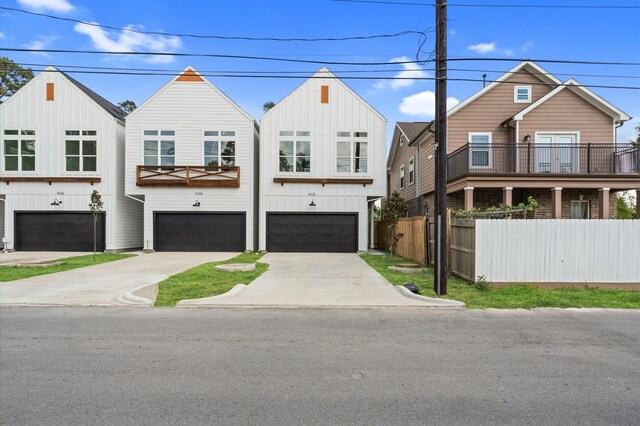 view of front of property with an attached garage, board and batten siding, fence, and driveway