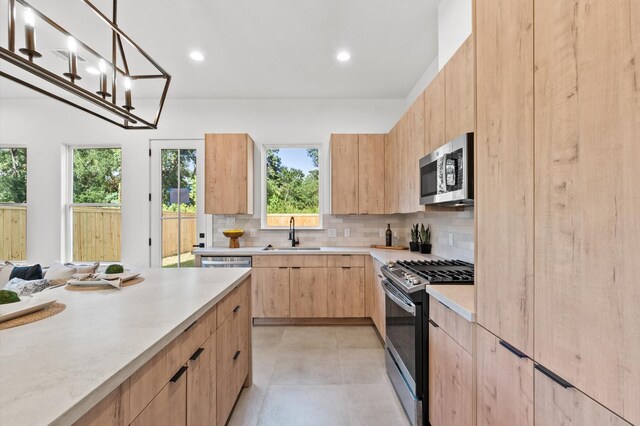 kitchen featuring light brown cabinetry, modern cabinets, light countertops, a sink, and appliances with stainless steel finishes