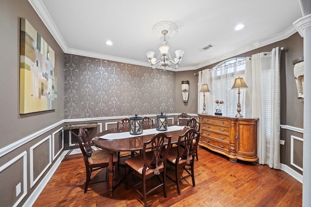 dining room with a notable chandelier, hardwood / wood-style flooring, and ornamental molding