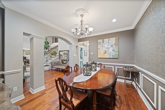 dining space featuring ornate columns, crown molding, wood-type flooring, and a chandelier