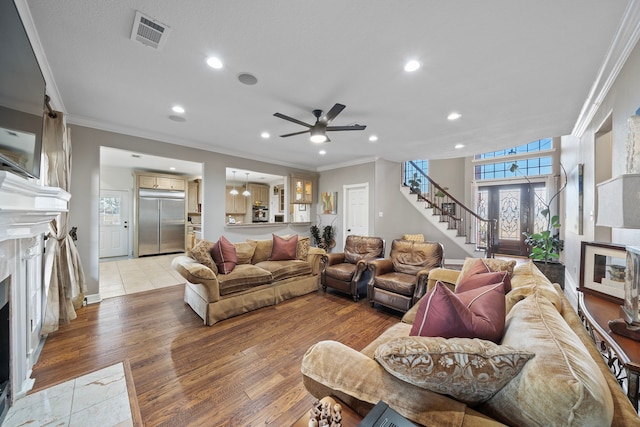 living room with crown molding, ceiling fan, a fireplace, and light hardwood / wood-style flooring