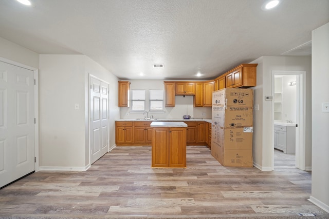 kitchen featuring a center island, a textured ceiling, and light wood-type flooring