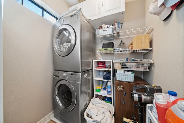 clothes washing area featuring stacked washer / dryer and cabinets