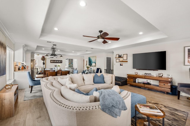 living room with a raised ceiling, ceiling fan, light hardwood / wood-style flooring, and ornamental molding