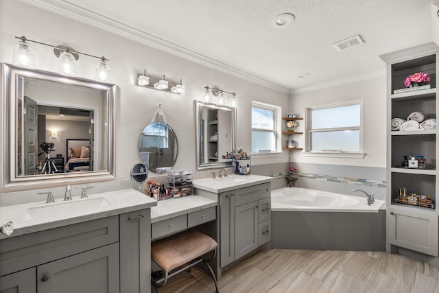 bathroom with a bathing tub, vanity, ornamental molding, and a textured ceiling