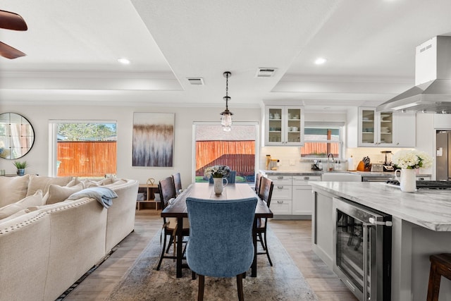 kitchen featuring pendant lighting, white cabinets, wine cooler, a breakfast bar area, and extractor fan