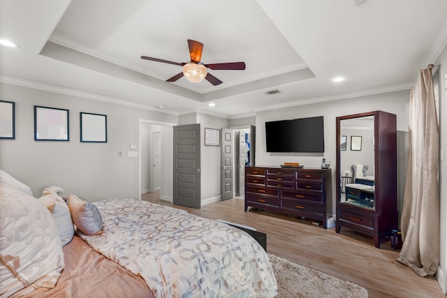 bedroom with light hardwood / wood-style floors, a raised ceiling, ceiling fan, and ornamental molding