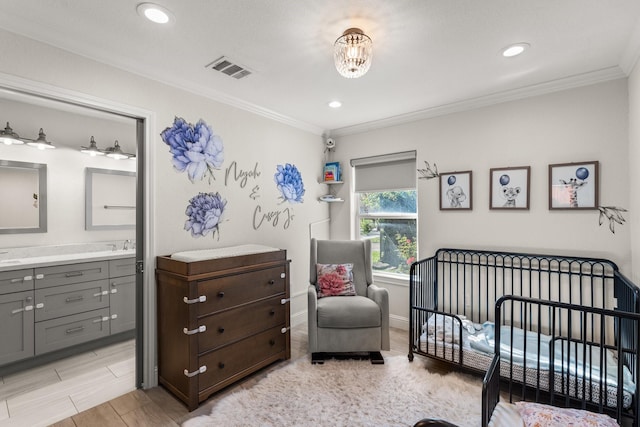 bedroom with a crib, connected bathroom, ornamental molding, and sink