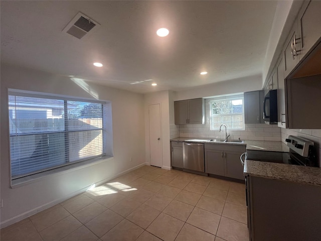 kitchen with light stone countertops, backsplash, sink, light tile patterned floors, and dishwasher