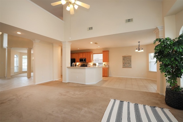 unfurnished living room with a high ceiling, light colored carpet, and ceiling fan with notable chandelier