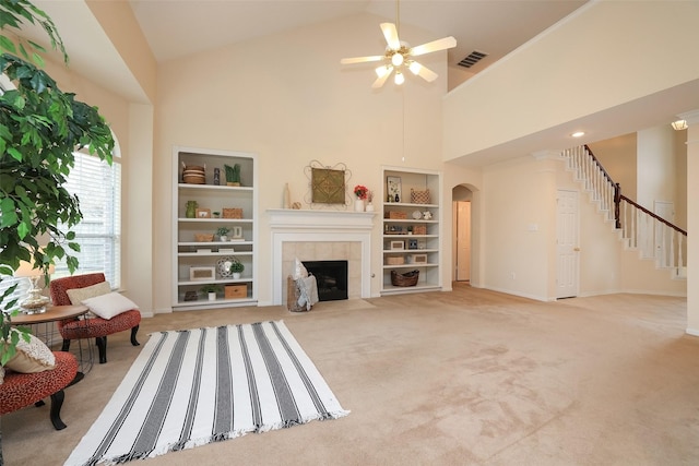 carpeted living room with high vaulted ceiling, built in shelves, ceiling fan, and a fireplace