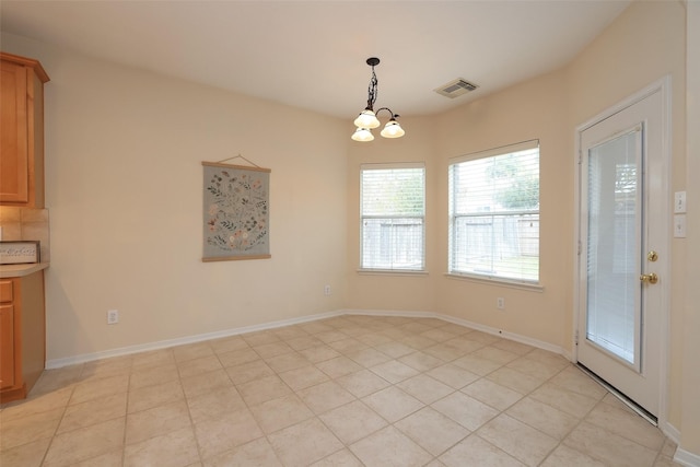 unfurnished dining area featuring light tile patterned flooring and a chandelier