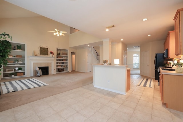 kitchen with light carpet, black fridge, kitchen peninsula, ceiling fan, and a tile fireplace