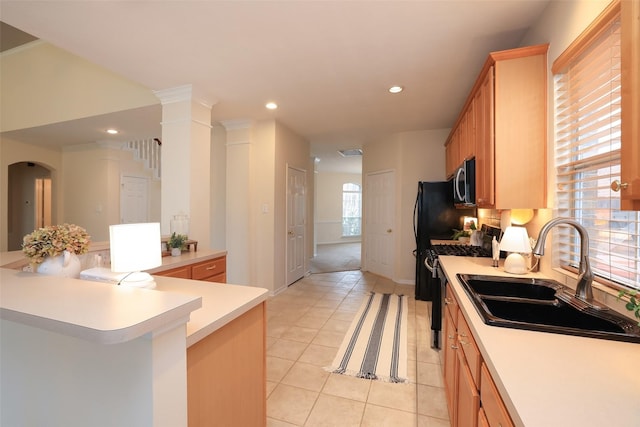 kitchen with light tile patterned floors, kitchen peninsula, sink, and range