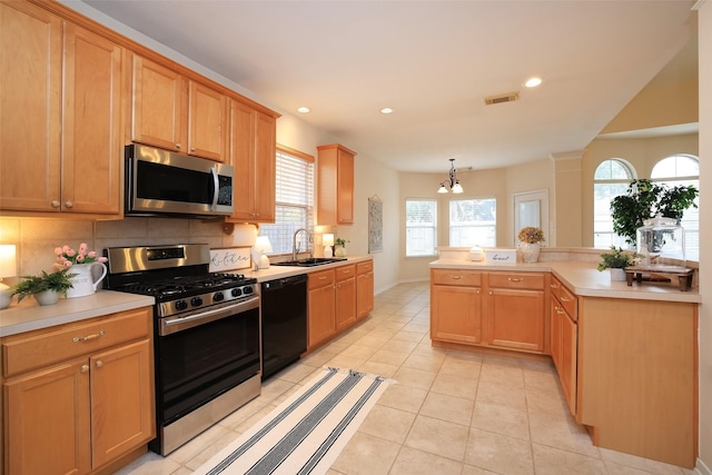 kitchen featuring kitchen peninsula, sink, an inviting chandelier, hanging light fixtures, and appliances with stainless steel finishes