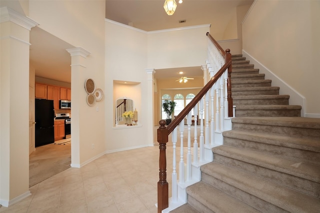 staircase with tile patterned flooring, crown molding, ceiling fan, and ornate columns