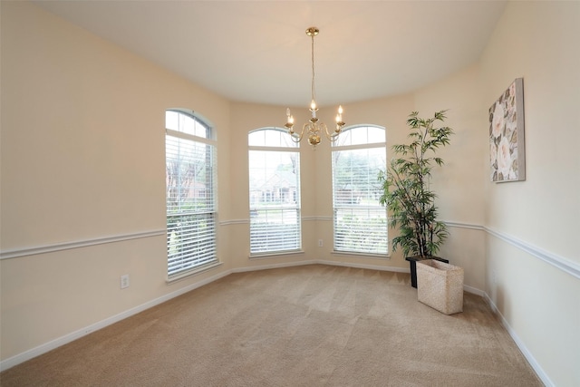 empty room with an inviting chandelier and light colored carpet