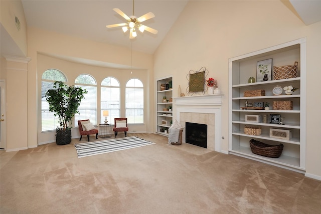 sitting room with ceiling fan, a healthy amount of sunlight, a tiled fireplace, and high vaulted ceiling