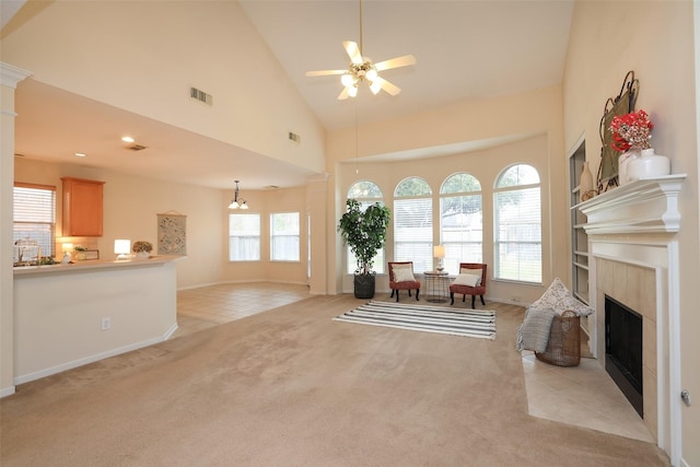 carpeted living room featuring ceiling fan, a tiled fireplace, and high vaulted ceiling