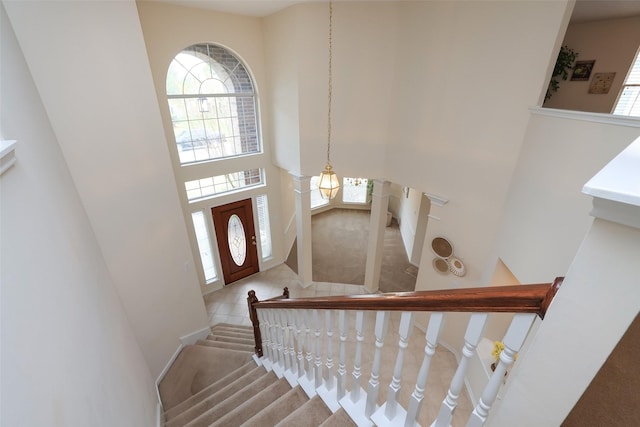 stairs featuring a high ceiling, tile patterned flooring, and an inviting chandelier