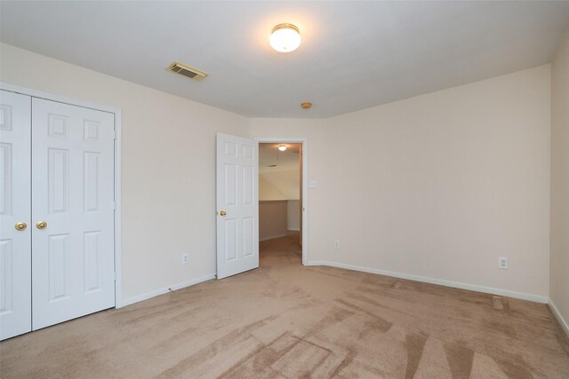 unfurnished bedroom featuring a closet and light carpet