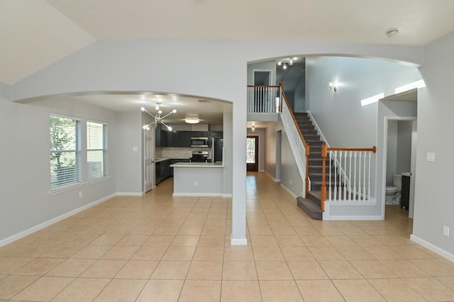 interior space featuring light tile patterned flooring, kitchen peninsula, appliances with stainless steel finishes, and vaulted ceiling