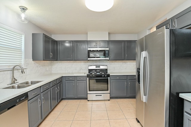 kitchen featuring gray cabinets, sink, light tile patterned floors, and appliances with stainless steel finishes