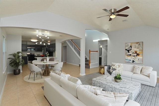 tiled living room with ceiling fan with notable chandelier and lofted ceiling