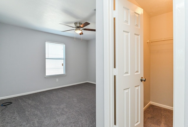 interior space featuring dark colored carpet and ceiling fan