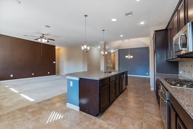 kitchen with dark brown cabinetry, sink, an island with sink, pendant lighting, and appliances with stainless steel finishes