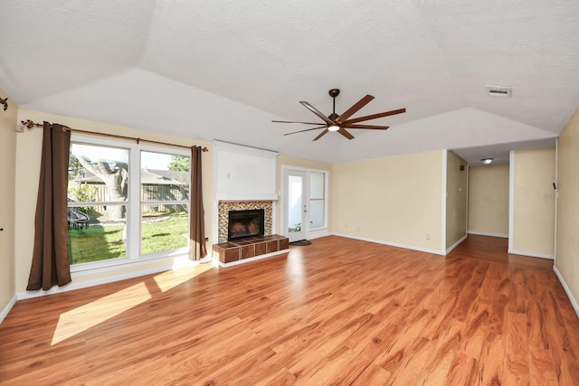 unfurnished living room with a tile fireplace, ceiling fan, light hardwood / wood-style floors, and a textured ceiling