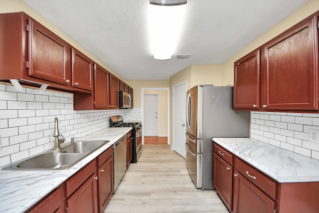 kitchen featuring backsplash, light hardwood / wood-style floors, sink, and stainless steel appliances