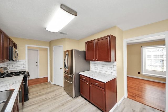 kitchen with light hardwood / wood-style floors, sink, stainless steel appliances, and tasteful backsplash