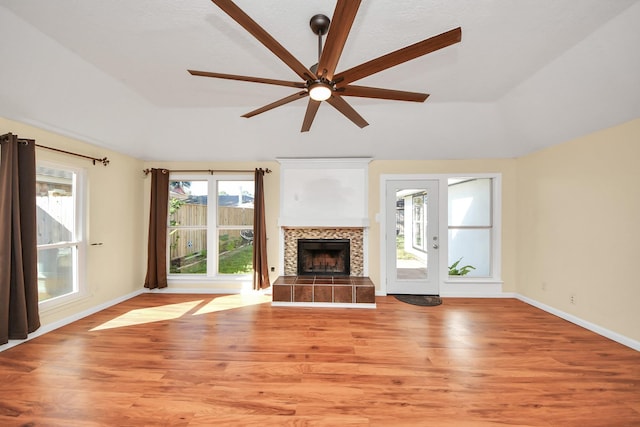 unfurnished living room with a tile fireplace, light hardwood / wood-style floors, and ceiling fan