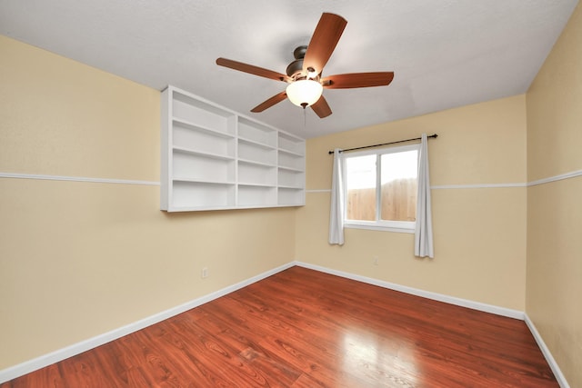 empty room with ceiling fan, wood-type flooring, and built in features